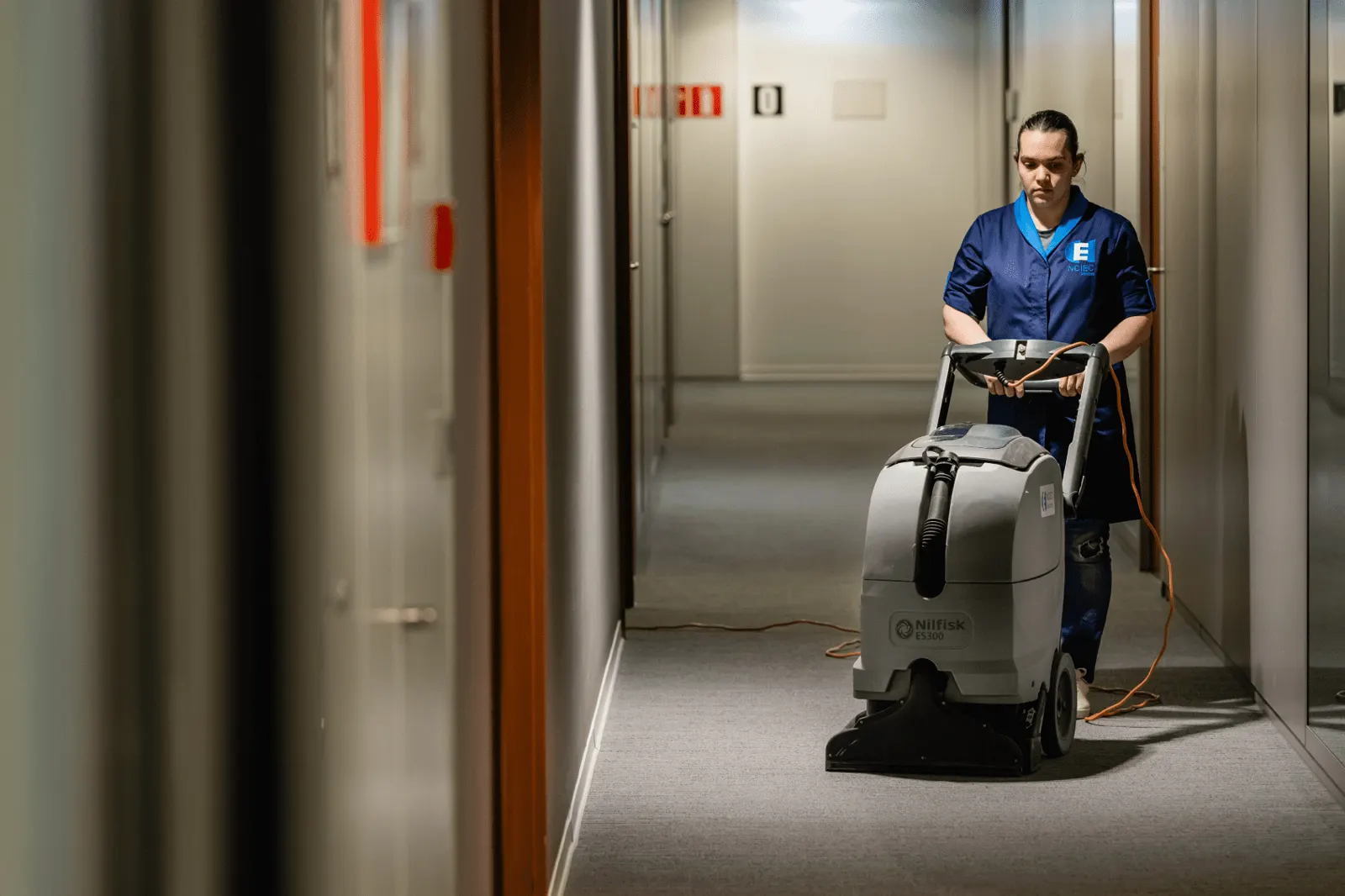 Agent NCIEC conduisant une autolaveuse dans un couloir de bureaux