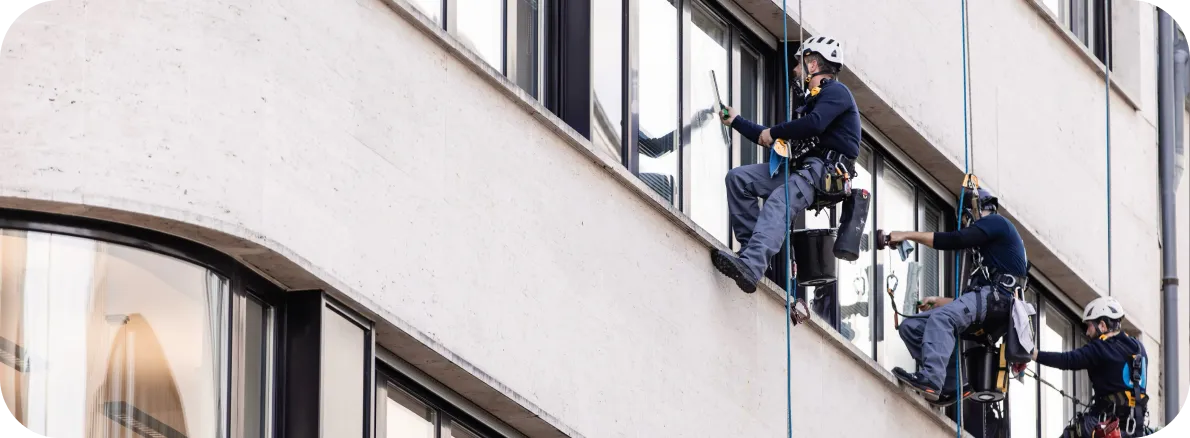 Trois cordistes NCIEC suspendus le long de la façade vitrée d’un immeuble