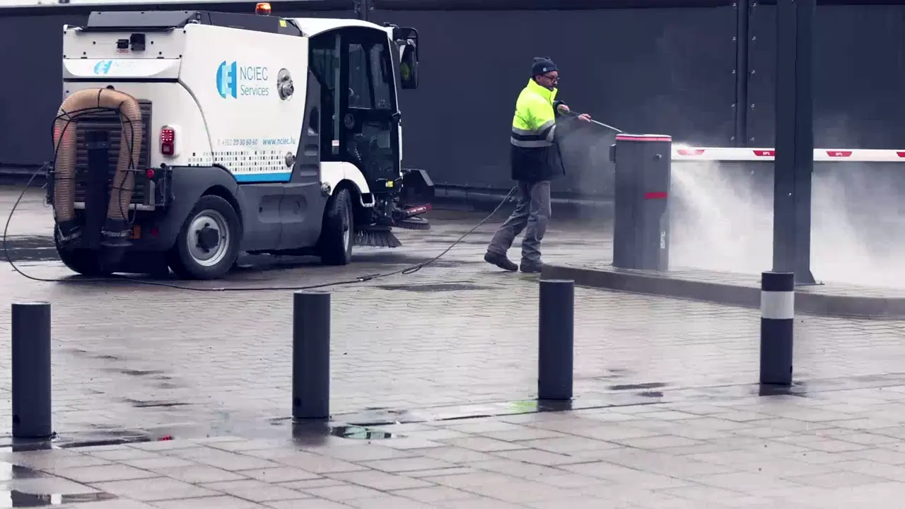 Balayeuse NCIEC et agent au nettoyeur haute pression sur une place pavée