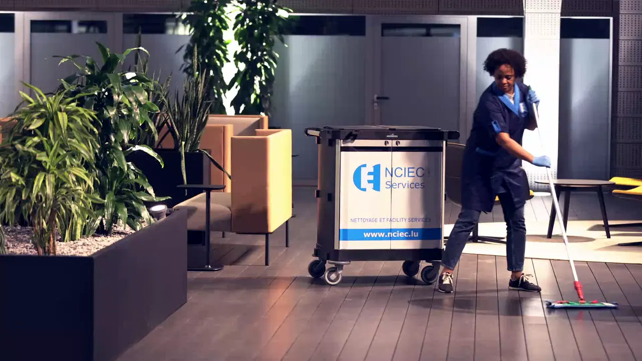 Agente NCIEC lavant le sol d’un hall avec son chariot de nettoyage